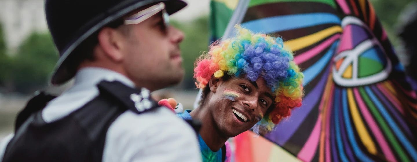 a man at an LGBTQ+ pride event smiling at a police officer who is also smiling